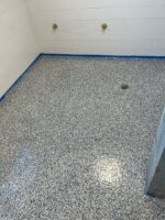 This showcases a gray floor that has recently received an epoxy flooring update that will enhance its durability and shine for the foreseeable future.